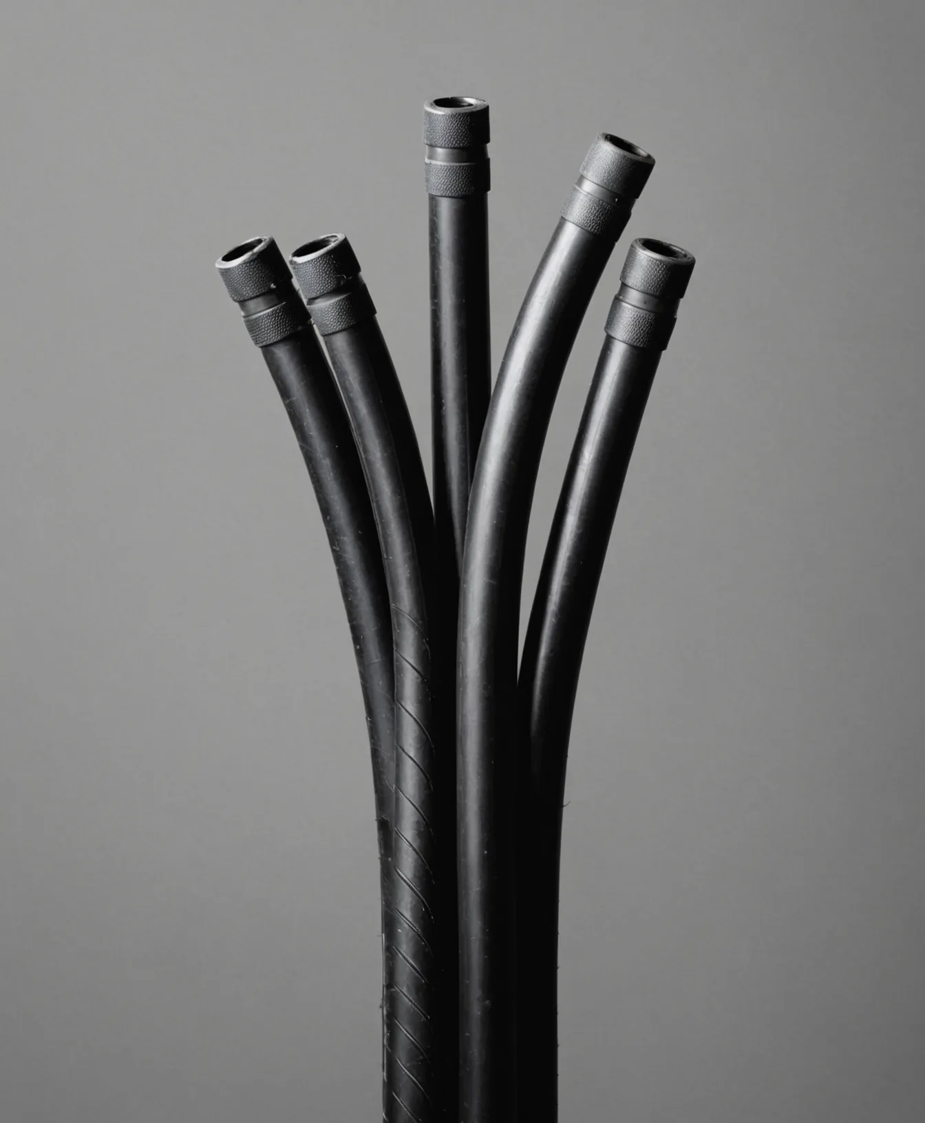 Five black bicycle brake cables with metal connectors fanned upward against grey background.